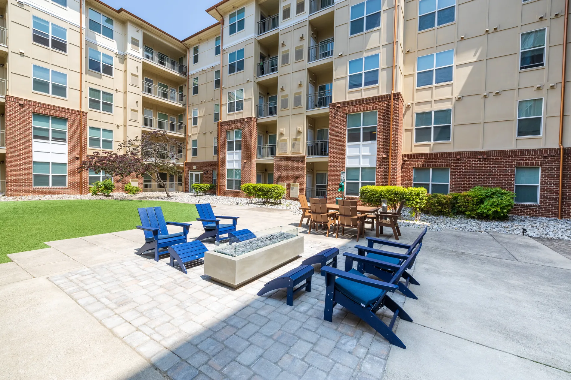 Courtyard fire pit surrounded by blue Adirondack chairs