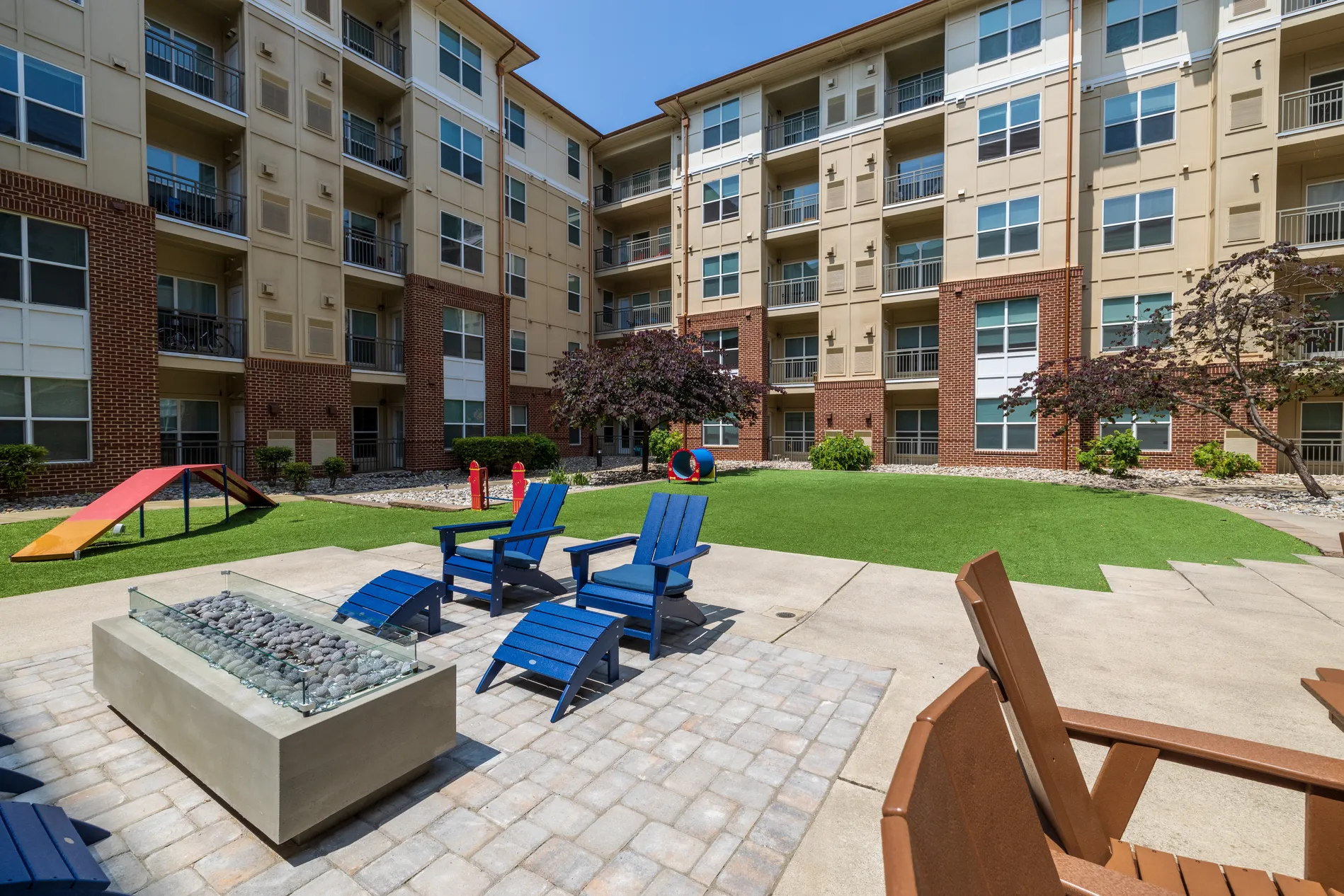 Courtyard pet park with agility ramps beside a fire pit and Adirondack chairs