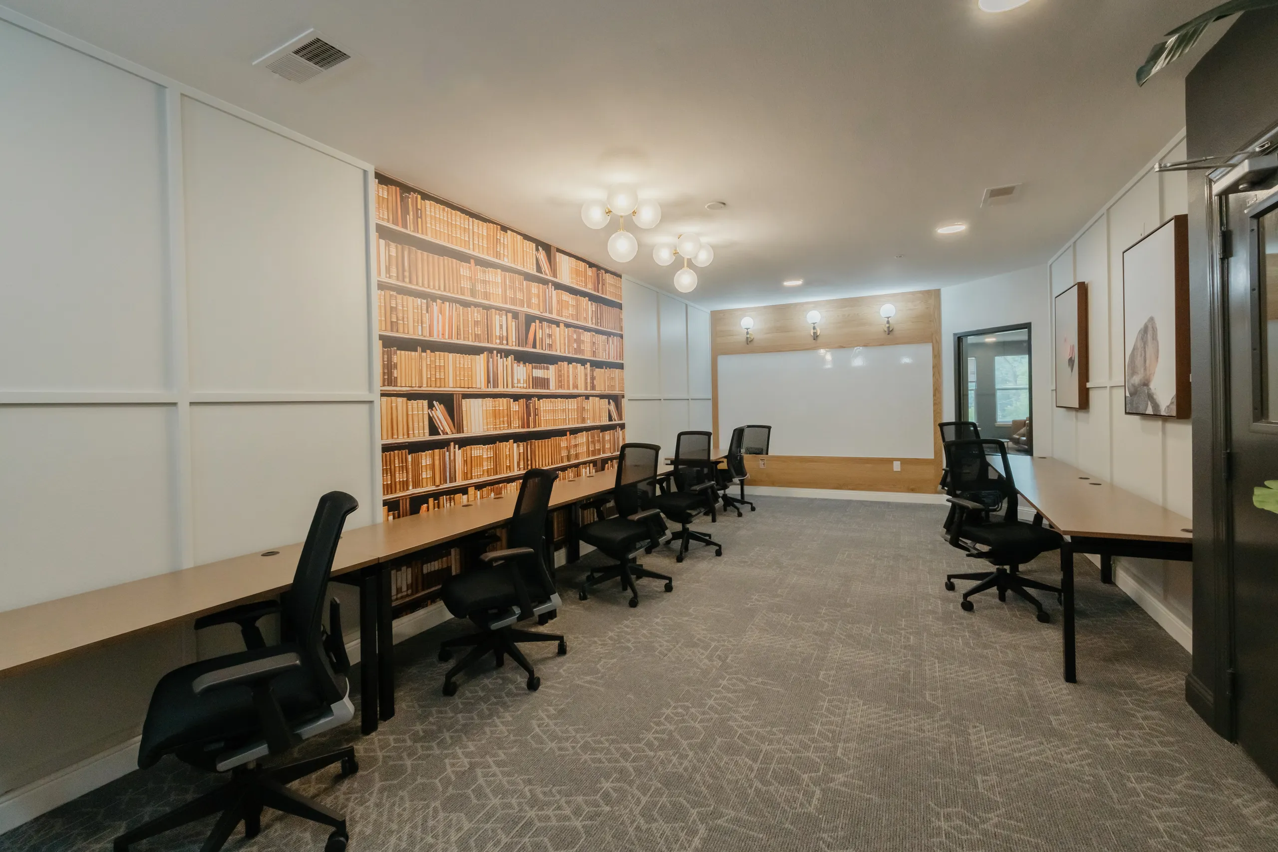 Study room with rows of desks and task chairs against a library wall