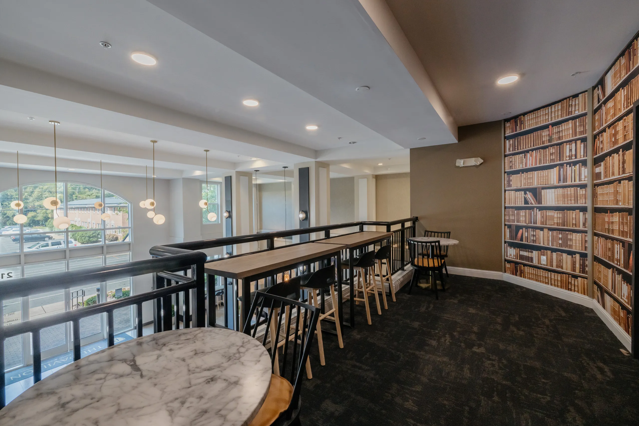 Mezzanine study counters overlooking the lobby beside a library wall