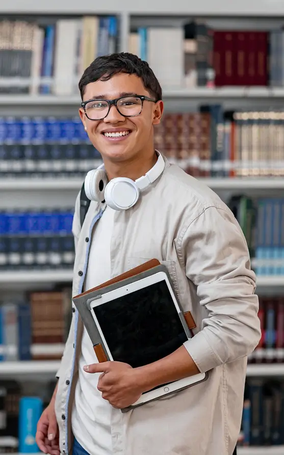a young man smiled inside a library while holding an ipad