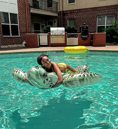a young woman smiles on a turtle float in a pool