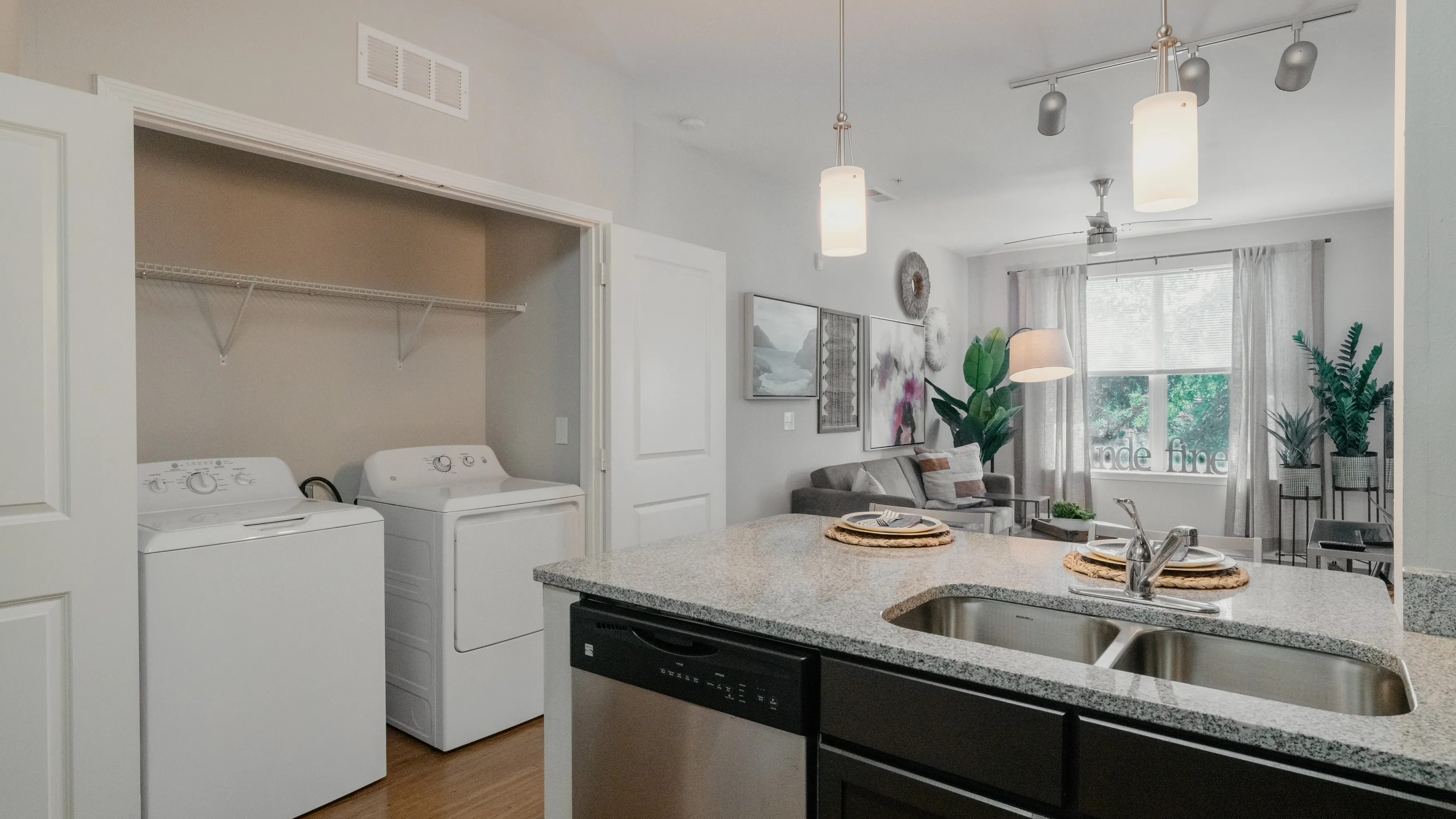 Apartment kitchen with granite counters beside an in-unit washer and dryer